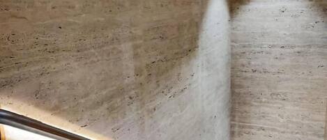 A modern interior with a polished concrete wall and a metal handrail.