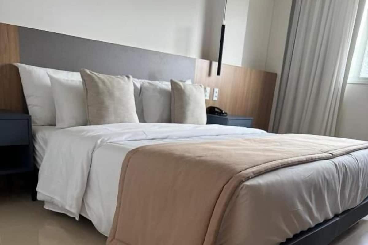 Ein modernes Hotelzimmer mit einem großen Bett, einem Holz-Kopfteil und einem Nachttisch.