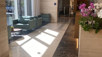 Un vestíbulo moderno con una zona de estar, un mostrador de recepción y una puerta de cristal que da a un baño.