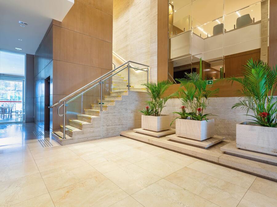 Een moderne lobby met een trap, plantenbakken en een glazen ingang.