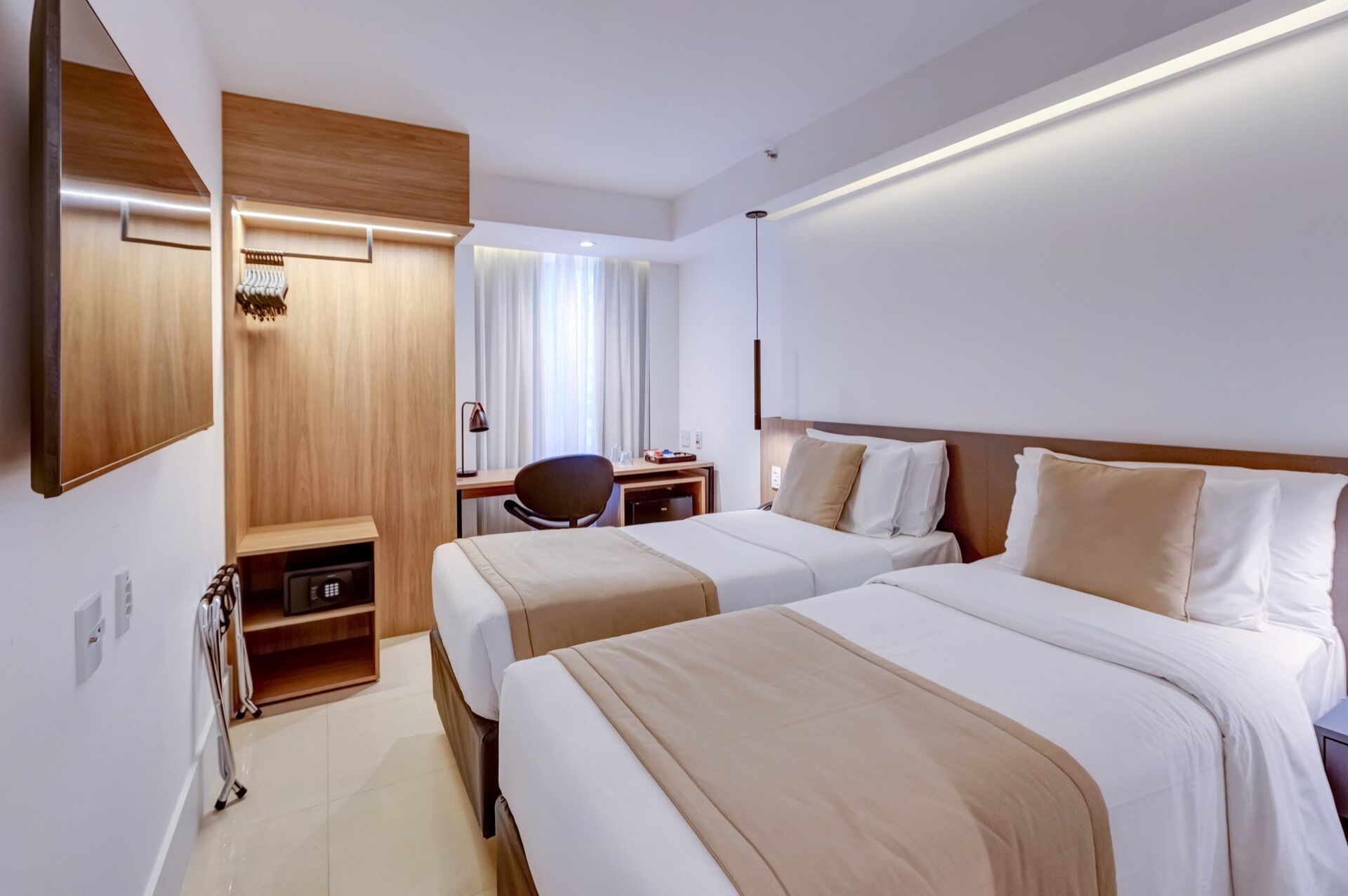 Ein Hotelzimmer mit zwei Betten, einem Schreibtisch, einem Stuhl und einem Spiegel.