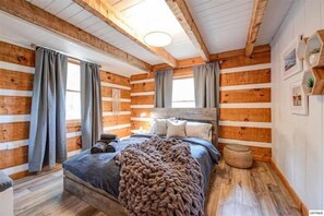 Une chambre confortable dans un chalet en rondins, avec un grand lit, des murs en bois et un plafond rustique.
