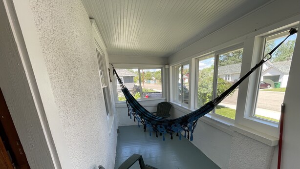 A covered porch with a hammock, a bench, and a view of the street.