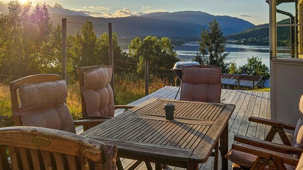 A wooden deck with a table and chairs overlooking a river and mountains. - Gorgeous home in Noresund with WiFi (Noresund)