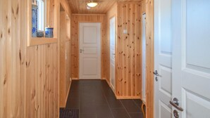 A narrow hallway with wooden walls and a black tiled floor. There are two white doors on the right, one with a silver handle. - Gorgeous home in Noresund with WiFi (Noresund)