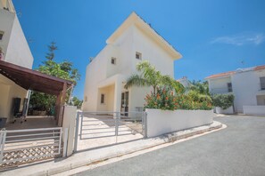 A residential building with a gated entrance, a covered porch, and a white exterior. - Protaras Delfini Villa Dv8 (Paralimni)
