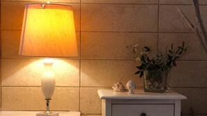Een badkamer met een wit wastafelmeubel, een wandlamp en een kleine plant op het meubel.