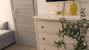 Een moderne kamer met een witte dressoir, een flatscreen televisie erboven, een grijze deur en een grijze bank.