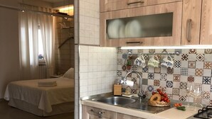 Een compacte keuken met houten kastjes, een betegelde spatwand en een klein eethoekje met een tafel en stoelen.