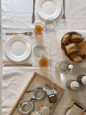A breakfast setting with plates, cutlery, glasses, and a tray with bread and condiments.