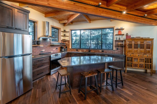 A modern kitchen with a large island, stainless steel appliances, and wooden accents. - Beautiful Japanese Pagoda (Bend)