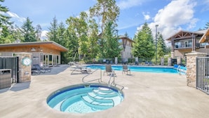 Un espace piscine comprenant un jacuzzi, des chaises longues et un bâtiment à la façade en pierre.