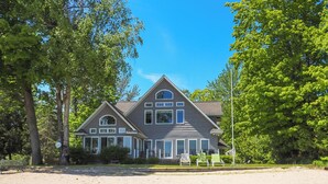 A large, two-story house with a symmetrical facade, multiple windows, and a prominent central chimney. - Spacious, Peaceful Lake House w/ Sandy Beach (Northport)