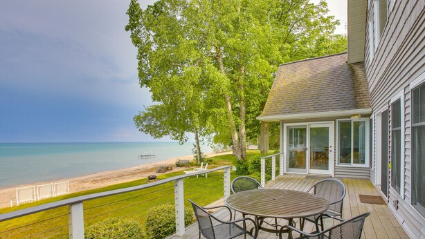 A deck with a table and chairs overlooking a beach. - Spacious, Peaceful Lake House w/ Sandy Beach (Northport)