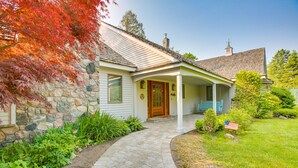 A house with a stone foundation, a porch with blue railings, and a front door with a small American flag. - Waterfront Suttons Bay: Wine Trail, Pickleball Ct (Suttons Bay)