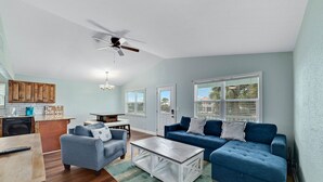 Ein Wohnzimmer mit einem blauen Sofa, einem Couchtisch und einem Deckenventilator.