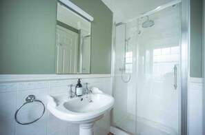 A bathroom with a white sink, a glass shower enclosure, and a mirror above the sink.