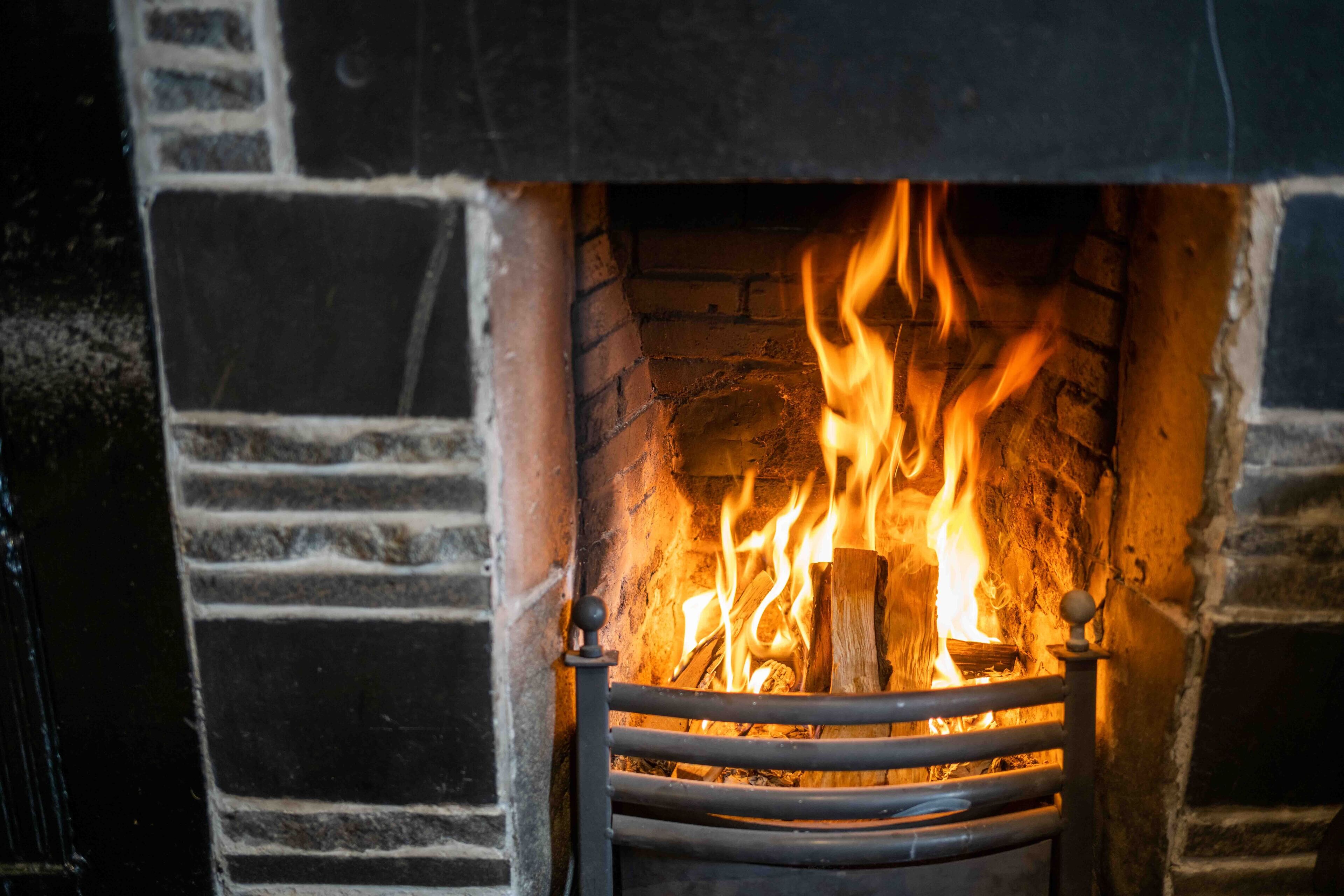 A fireplace with a fire burning inside, surrounded by a brick wall.