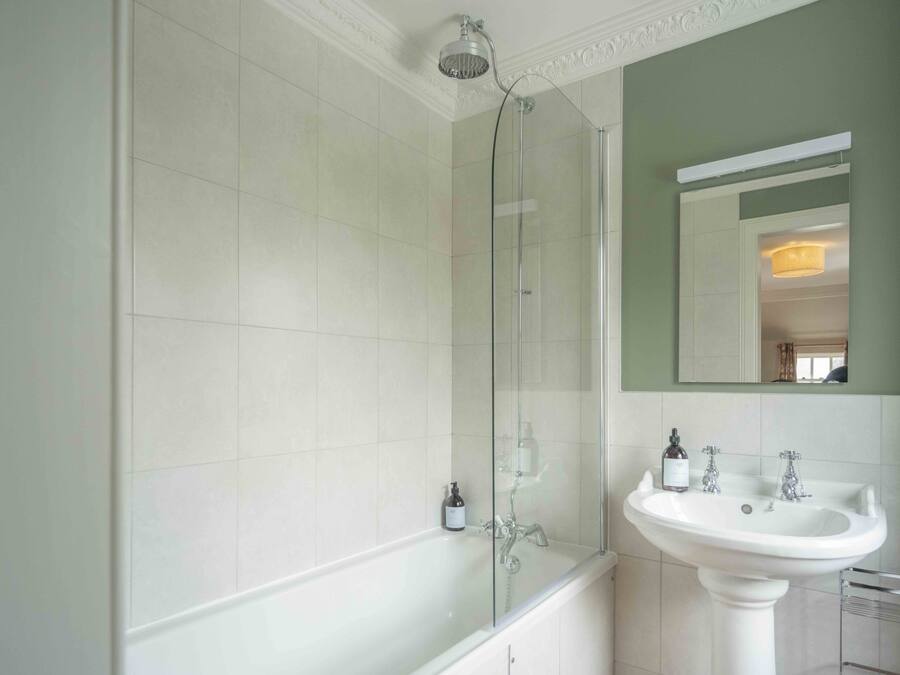 A bathroom with a glass-enclosed shower, a white sink, and a mirror above the sink.