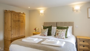 A neatly made bed with a headboard, a wooden wardrobe, and bedside tables with lamps.