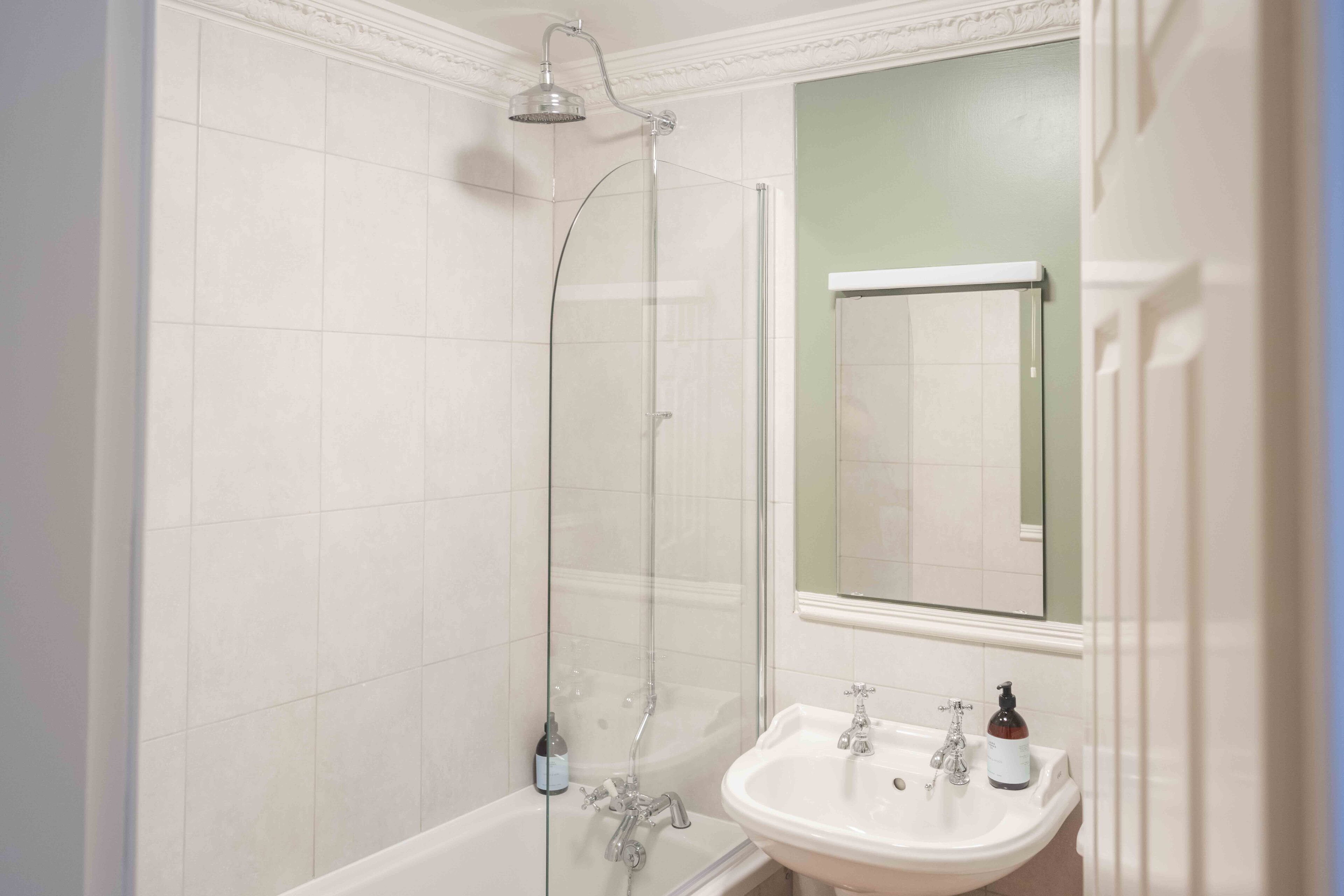 Une salle de bain avec une douche à parois de verre, une baignoire blanche et un lavabo surmonté d’un miroir.