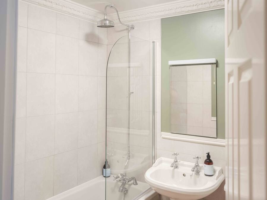 Une salle de bain avec une douche à parois de verre, une baignoire blanche et un lavabo surmonté d’un miroir.