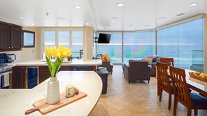 A modern kitchen with a large island, a dining area with a view of the ocean, and a living area with a flat-screen TV. - Oceanfront Penthouse: Luxury Views, A/C & Parking! (San Diego)