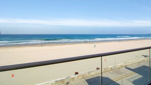 A beach view from a balcony with a clear sky and calm sea. - Oceanfront Penthouse: Luxury Views, A/C & Parking! (San Diego)