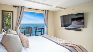 A hotel room with a large bed, a TV, a balcony with a view of the ocean, and a chair. - Oceanfront Penthouse: Luxury Views, A/C & Parking! (San Diego)
