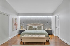 A bedroom with a large bed, bedside tables, a bench, and a painting on the wall. - Luxe Lakefront Escape - Jacuzzi +Pool + Sunset Views + BBQ + Close to Disney! (Davenport)