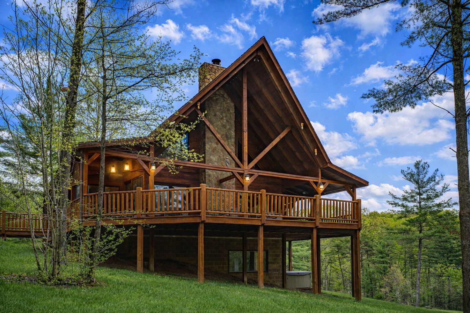 A cabin with a wooden deck, a stone chimney, and a large window.