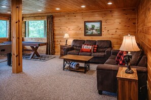 L’intérieur chaleureux d’un chalet, avec un revêtement mural en bois, un ensemble de canapés, une table basse et une table à manger.