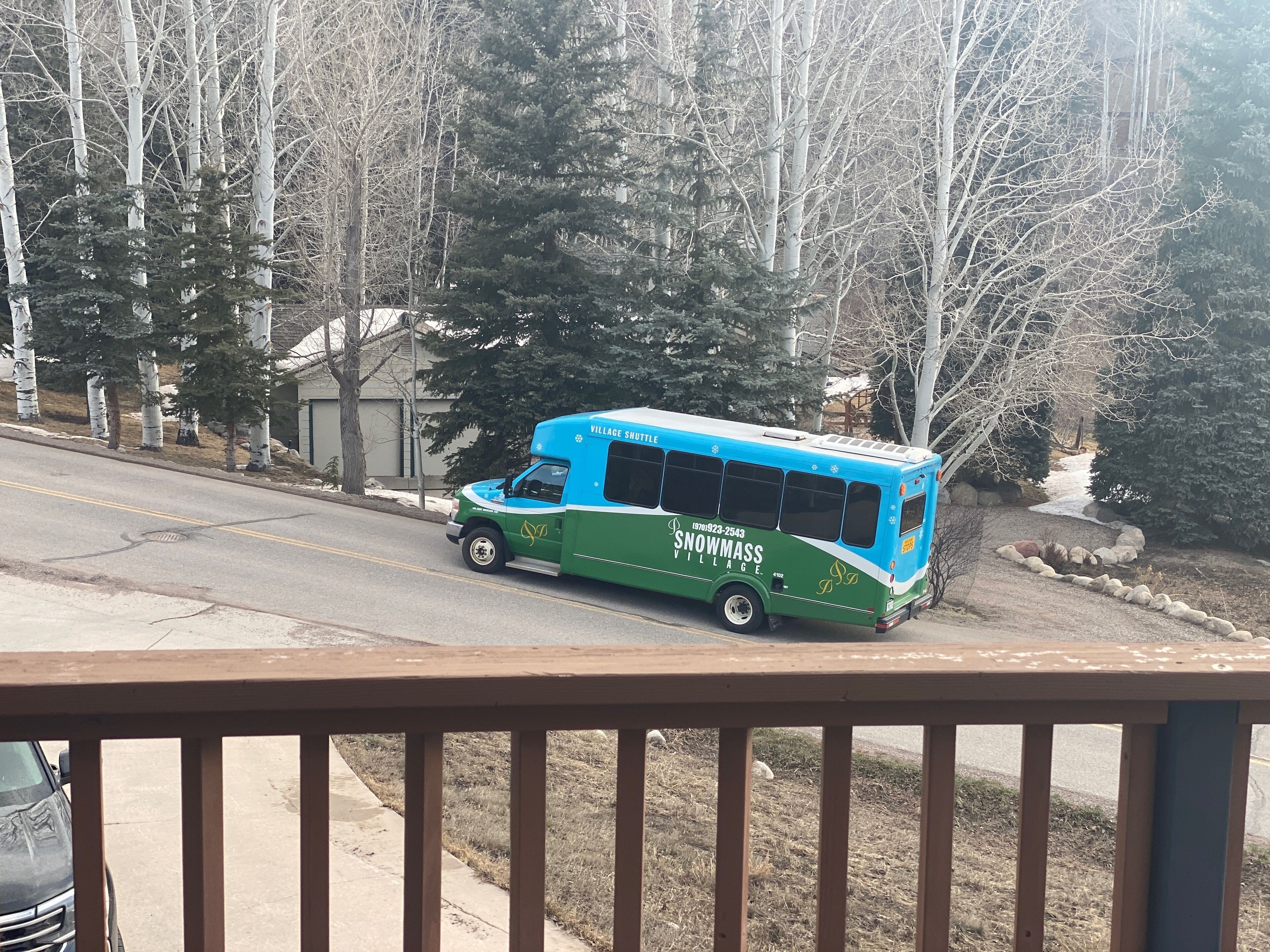 Shuttle bus at end of driveway seen from the deck.