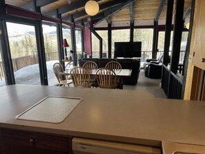 A wooden deck with a dining area featuring a table and chairs, a sofa, and a TV.