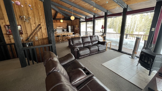 A cozy cabin interior with a leather sofa, wooden beams, a kitchen area, and a view of the outdoors. - Classic Chalet on free shuttle route-fireplace, hot tub and sauna.

5 Bedrooms (Snowmass Village)