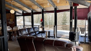 A cozy cabin interior with a leather sofa, wooden ceiling beams, and a large window overlooking a snowy landscape. - Classic Chalet on free shuttle route-fireplace, hot tub and sauna.

5 Bedrooms (Snowmass Village)