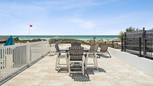 Un patio con mobiliario exterior y vista a la playa.