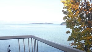 A balcony with a view of calm water and distant land. - Ocean Front Condo (Parksville)