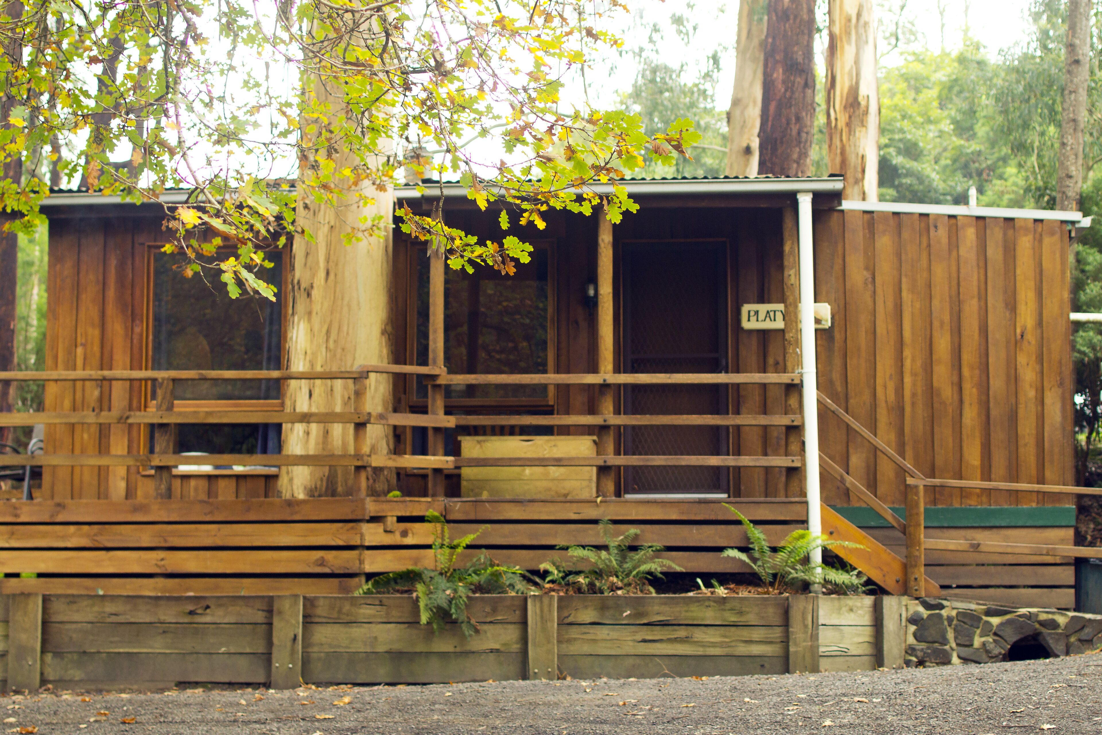 A wooden cabin with a porch, a staircase, and a sign that reads "PLATY".