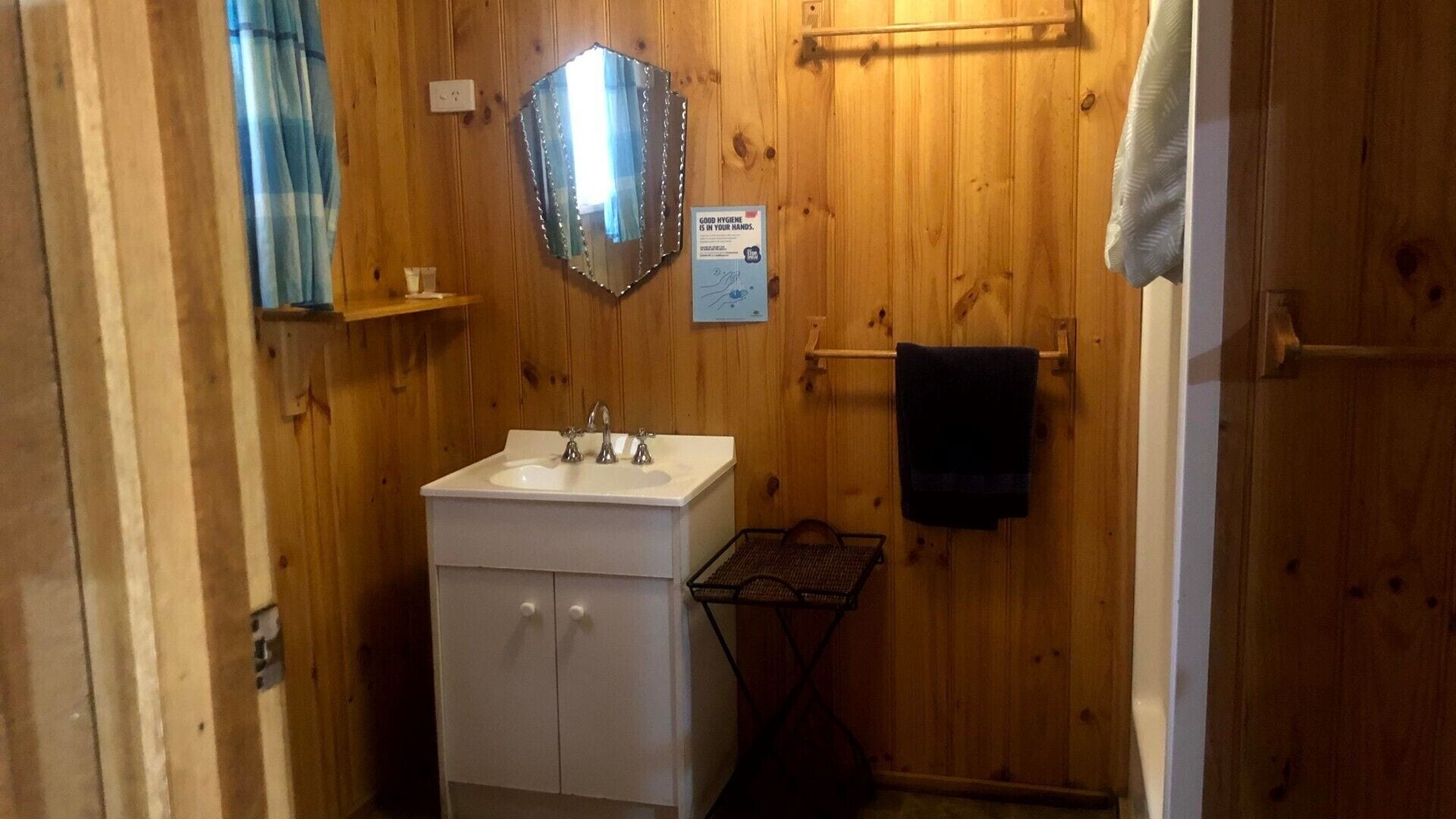 Un baño pequeño con paneles de madera, un lavabo blanco, un espejo y un perchero para toallas.