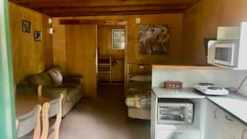 Een gezellige kamer met een bank, een klein tafeltje, een magnetron, een broodrooster en een schilderij van een koala aan de muur.