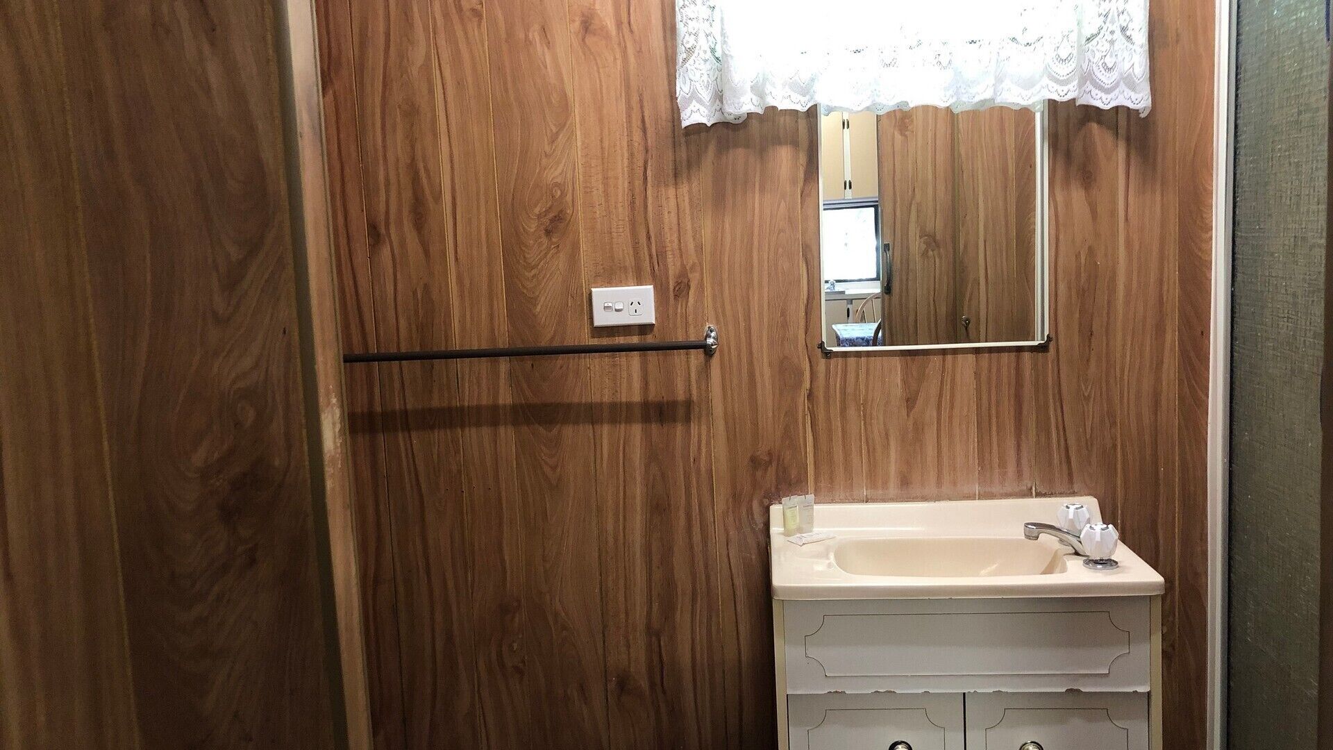 A wooden bathroom with a white sink, a mirror, and a towel rack.