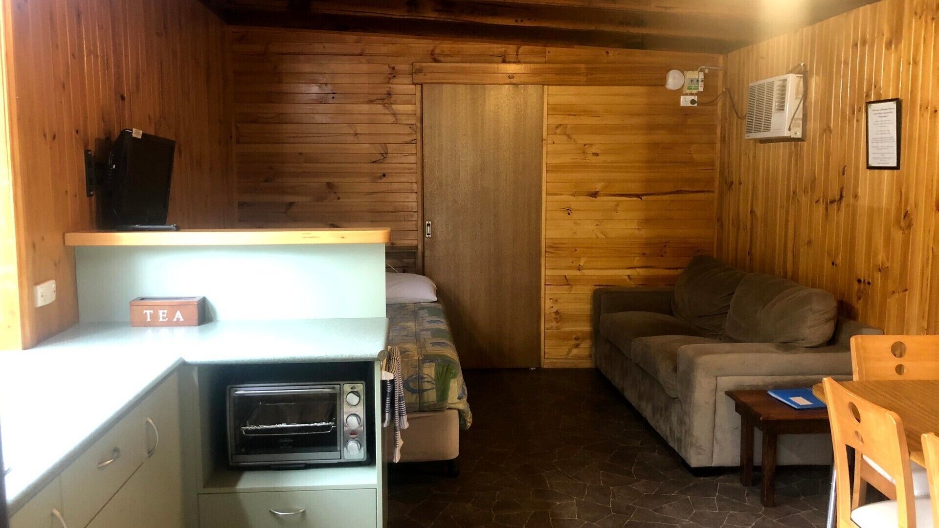 Une pièce compacte comprenant un coin cuisine, un lit, un canapé et une petite table.