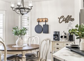 Uma área de refeições com um candelabro, um espaço para café e uma placa na parede com a inscrição 'Coffee'.
