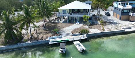 A coastal property with a large house, a dock with boats, and a clear view of the water.