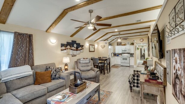 A cozy living room with a sofa, armchair, and coffee table, a dining area with chairs, and a kitchen with white cabinets. - StockYards! Less than 4 minutes-Sleeps 8-Lee House, TCU close by (Fort Worth)