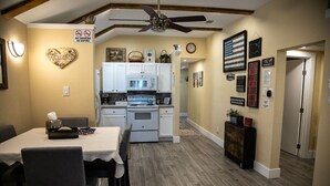 A kitchen with white cabinets, a microwave, and a stove. There is a dining table with chairs and a 'Welcome' sign on the wall. - StockYards! Less than 4 minutes-Sleeps 8-Lee House, TCU close by (Fort Worth)