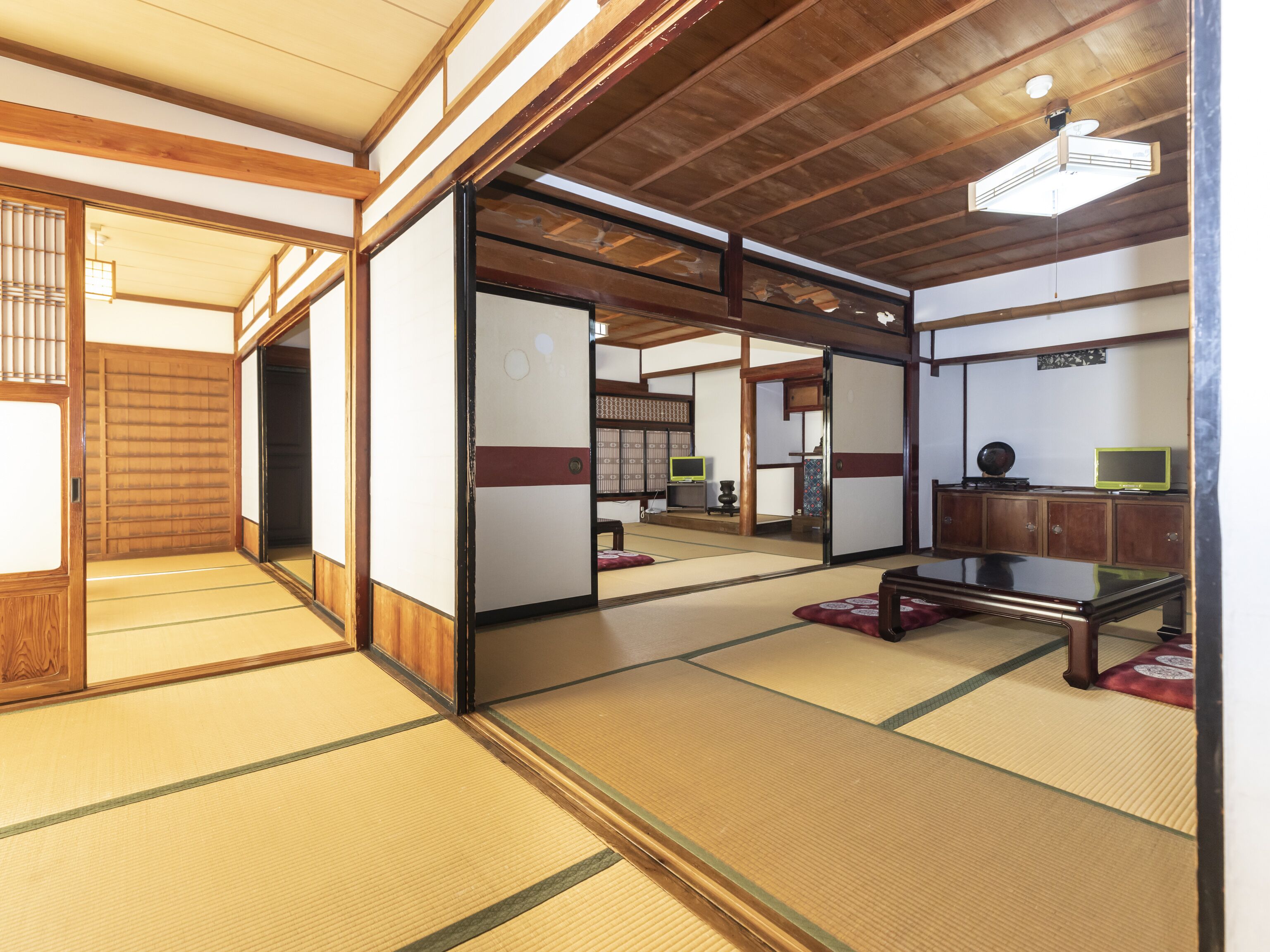 Una habitación japonesa tradicional con suelo de tatami, puertas correderas y techo bajo con vigas a la vista.