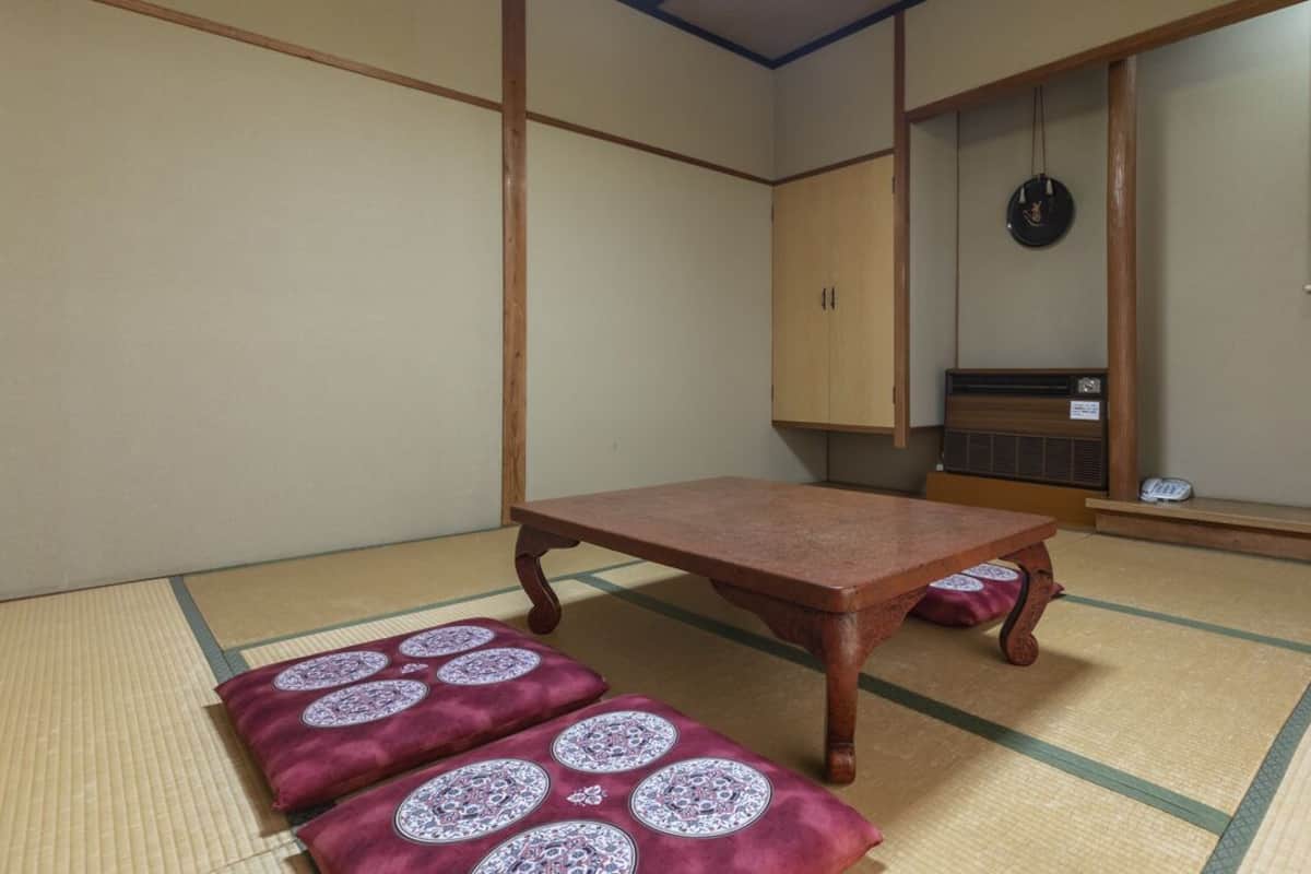 Une pièce de style japonais traditionnel, avec un sol recouvert de tatamis, une petite table en bois et un futon servant de lit.