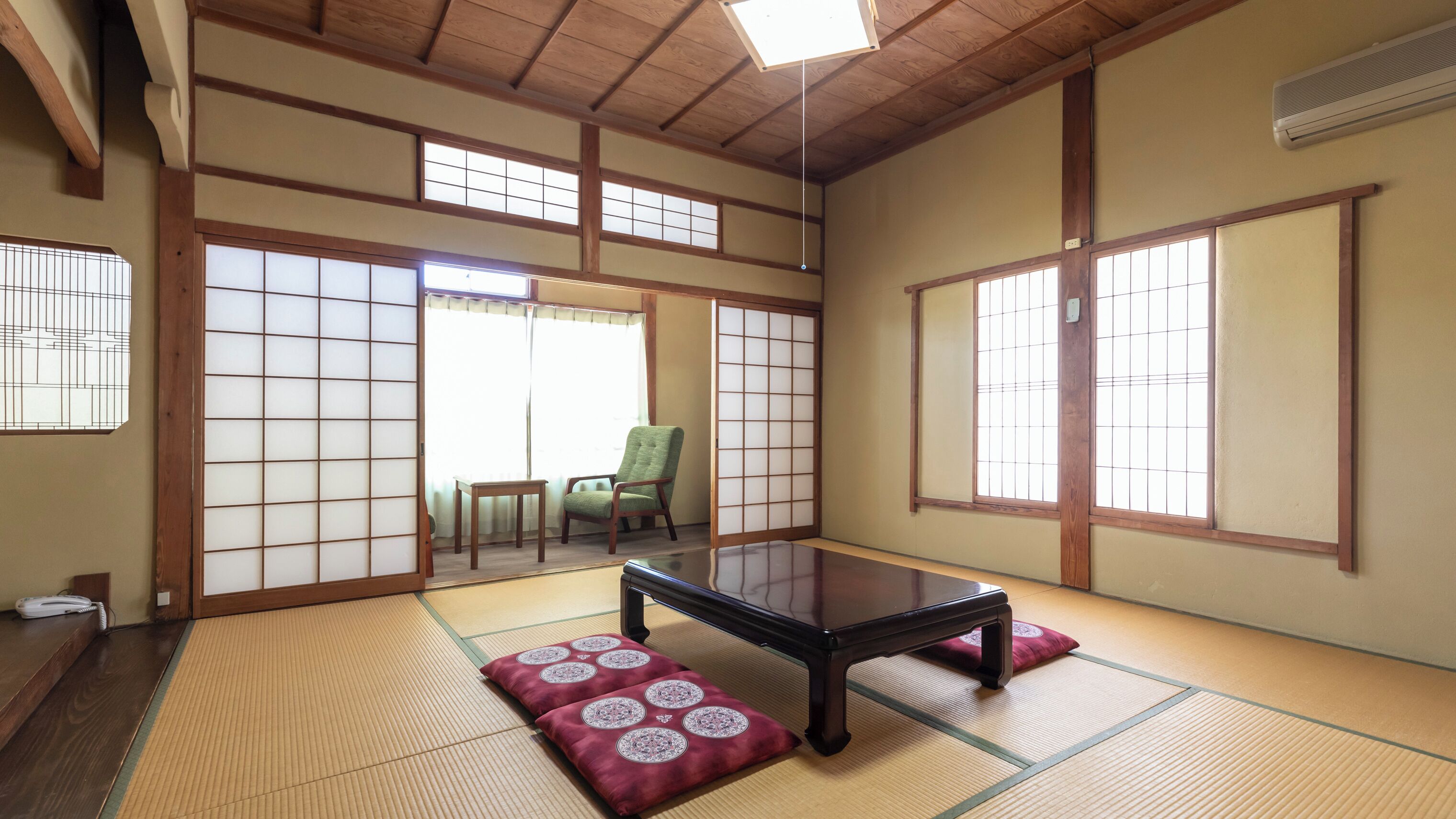 A traditional Japanese room with tatami flooring, shoji screens, and a low table.